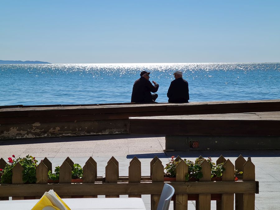 Ältere Männer sitzen diskutierend am Meer